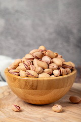 Wall Mural - Pistachios on wooden background. Pistachios or pistacia vera in a bowl.