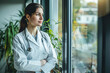 © Tymofii Borysenko - Female doctor standing at hospital and looking through window