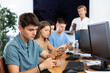 © JackF - Positive guy student of computer courses sits among students and holds mobile phone in hands, plays game, tests new application