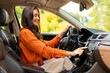 © Home-stock - Happy European woman driving car and choosing road playlist for listening to music on auto audio system, pushing button on dashboard