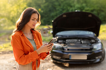 Sad woman has broken down car on roadside, feeling stressed, calling and searching for help. Emergency assistance or insurance service.