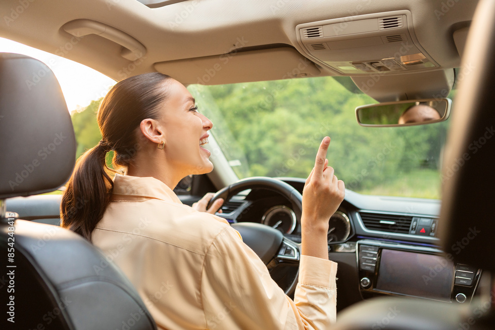 Happy excited young woman driver sitting in front seat, holding auto ...