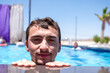 © Viga - A man in a pool, resting his chin on the edge while smiling at the camera. The scene is bright and sunny