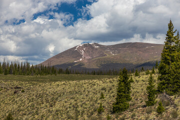 Wall Mural - Mountain peak with clouds and forest valley