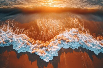 Sunset aerial view of waves crashing on sandy beach