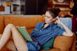 © SHOTPRIME STUDIO - Young woman sitting on couch with crossed legs reading a book in denim shirt leisure activity at home