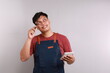 © ArvStd - Asian barista man in blue apron taking order, writing on menu book list, thinking with pen on head. Isolated image on white background