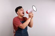 © ArvStd - Young asian man barista barman employee wear blue apron work in coffee shop standing while holding a megaphone