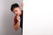 © ArvStd - Funny curious asian man in blue apron peeking behind the wall