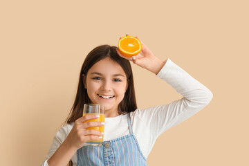 Wall Mural - Little girl with glass of juice and orange on beige background