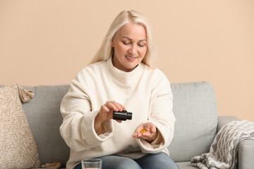 Sticker - Beautiful mature woman with pills bottle and glass of water at home