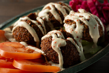 A closeup view of a plate of falafels, with tahini drizzle.