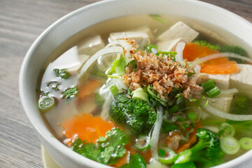 Wall Mural - A closeup view of a veggie pho bowl with chicken broth.