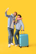 © Pixel-Shot - Couple of young tourists with passports and suitcase taking selfie on yellow background
