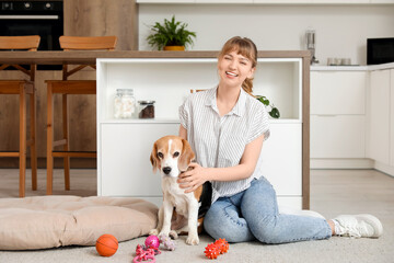 Wall Mural - Young woman with cute beagle dog and toys sitting on floor at home