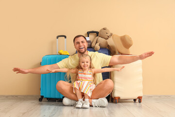 Poster - Young happy father and his little daughter with suitcases near beige wall