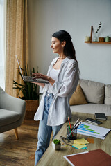 Wall Mural - A stylish woman in a living room, holding a laptop.