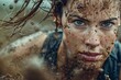 © Elmira - A close-up image of a young woman participating in a rugged obstacle course race, her face covered in mud as she navigates through a challenging terrain