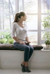 Wall Mural - Young woman relaxing next to a window