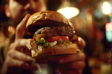 A person holding a juicy hamburger for a meal or snack