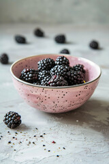 Wall Mural - A bowl of blackberries sits on a grey surface