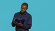 © DC Studio - Portrait of security guard holding clipboard, taking notes while overseeing premises. Private law enforcement worker using pen to write down orders received, studio backdrop, camera A