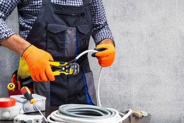 Wall Mural - electrician worker striping the insulation of wires. electrician working against concrete wall.