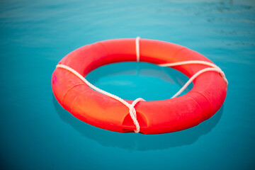 Red swim tube floating on blue water in water park for pubic security purpose.