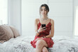 © StockPhotoPro - Woman sitting on the bed and chatting with her phone