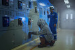 © pinyo - Electrical worker wearing arc flash suit protection is used to draw out a large circuit breaker.
