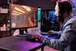 © DC Studio - Gamer using professional grade level gaming PC to avoid disruptive lag while playing esports competitions. Man relaxing in cozy apartment playing action shooter videogame late at night