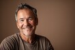 © CogniLens - Portrait of a satisfied caucasian man in his 50s smiling at the camera isolated on soft brown background