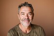 © CogniLens - Portrait of a satisfied caucasian man in his 50s smiling at the camera over soft brown background