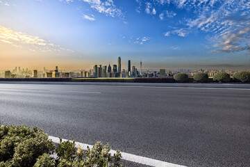 Wall Mural - Empty asphalt road and cityscape in modern city at sunset