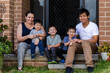 © Austockphoto - Happy mixed race Chinese Australian family sitting together on front doorstep of home