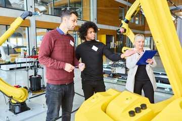 engineers discussing programming and training of robotic arms in a modern industrial facility