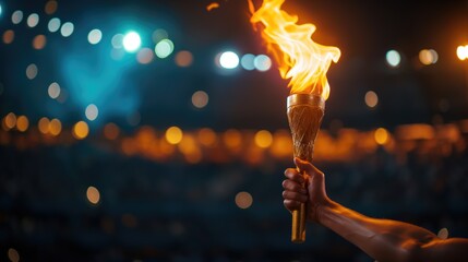 A hand holds a torch with the olympic flame against a night stadium. Sport concept	
