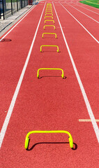 Looking down at yellow mini hurdles set up for speed training in lane on a track