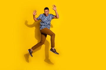 Wall Mural - Full length photo of cheerful positive guy dressed print shirt jumping high running empty space isolated yellow color background