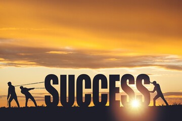 Silhouettes of people drawing the word SUCCESS on a sunset background, business concept