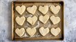 © AI - Heart-shaped portions of cookie dough on a baking sheet.