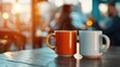 © IYearDesign - Coffee and a Good Conversation, Two coffee mugs placed next to each other on a table with a blurred background of two people talking Casual attire like a blazer or a blouse