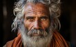 © imagineRbc - A man with a beard and white hair is wearing an orange scarf. He has a serious expression on his face