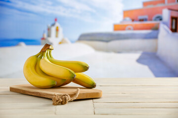 Bananas on white wooden board table and white terrace background