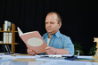 © Bliss - A man with inclusivity sits at a desk reading a book.