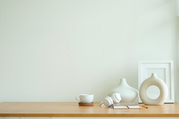 Wall Mural - Empty picture frame on wooden  table with modern white ceramic vase.