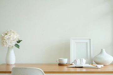 Wall Mural - Empty picture frame, coffee cup, headphone and ceramic vase on wooden table.