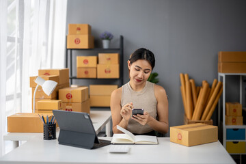 A woman is sitting at a desk with a laptop and a cell phone