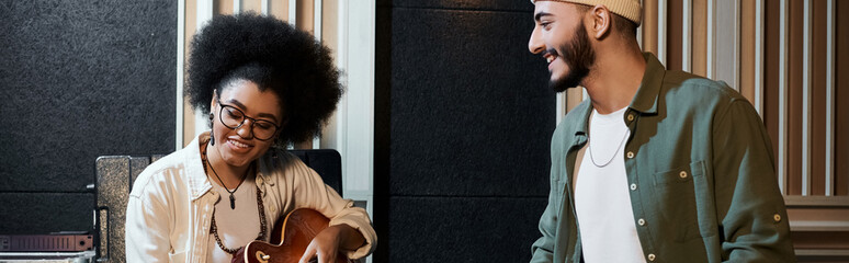 A man and a woman collaborate in a recording studio, working on music for their band rehearsal.