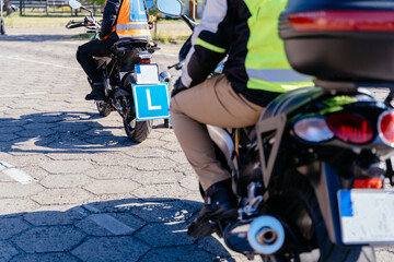 Wall Mural - Two people on motorcycles with a blue L on the back. One of the riders is wearing a yellow vest